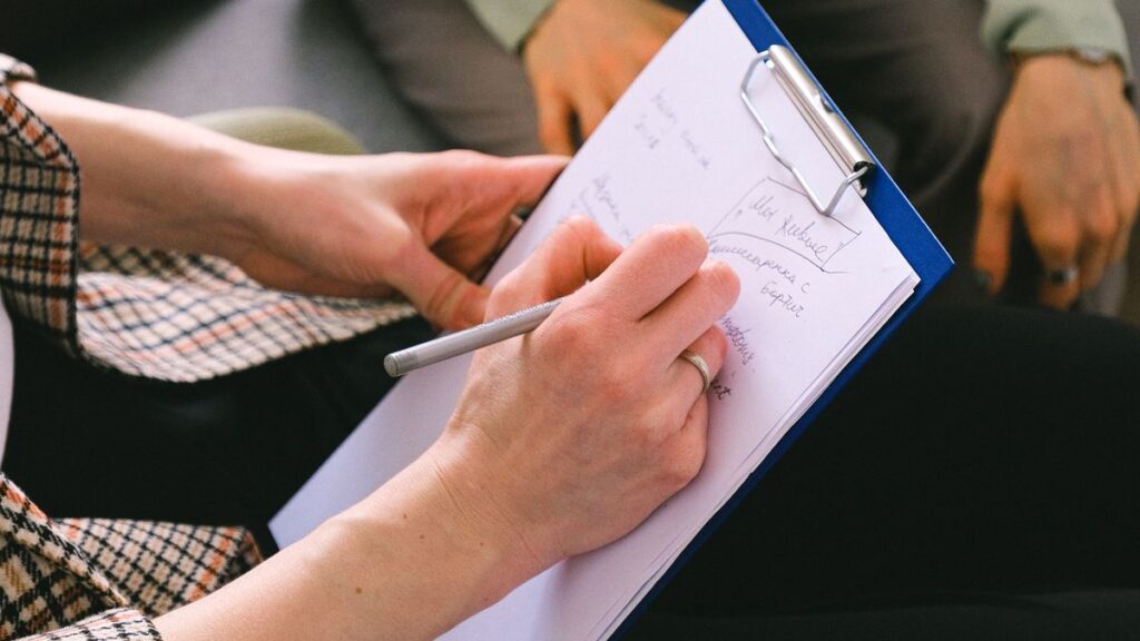 Adviser taking notes while talking with clients about a complaint