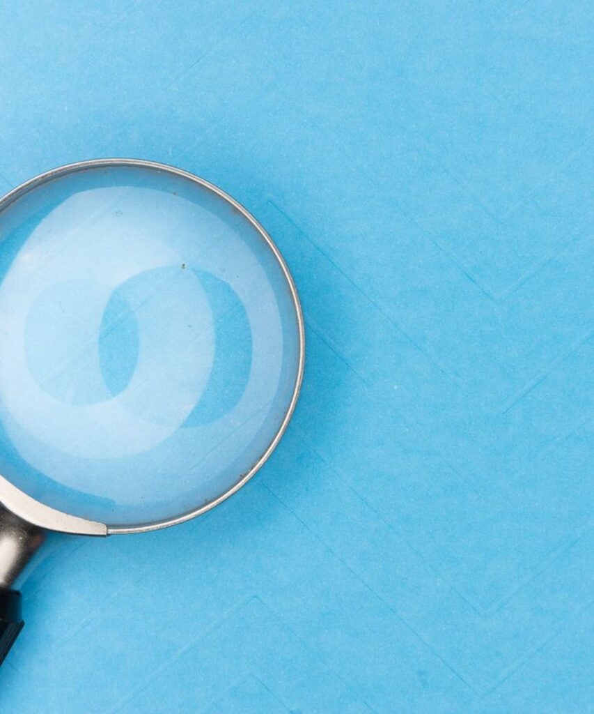 Magnifying glass on a blue background, representing reading the fine print