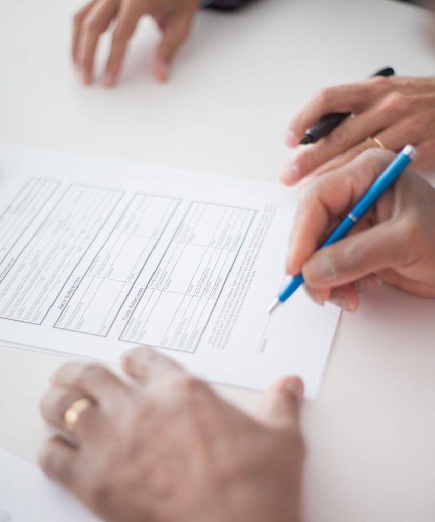 Hands signing an agreement form with a pen