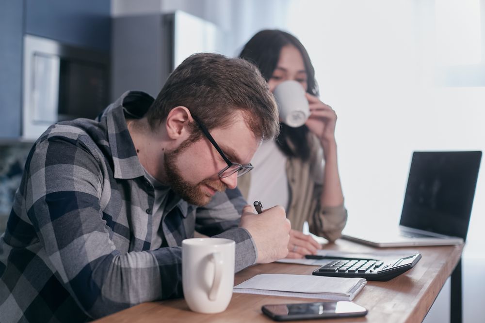 Couple going through household finances at a table, learning how to budget at the kitchen table