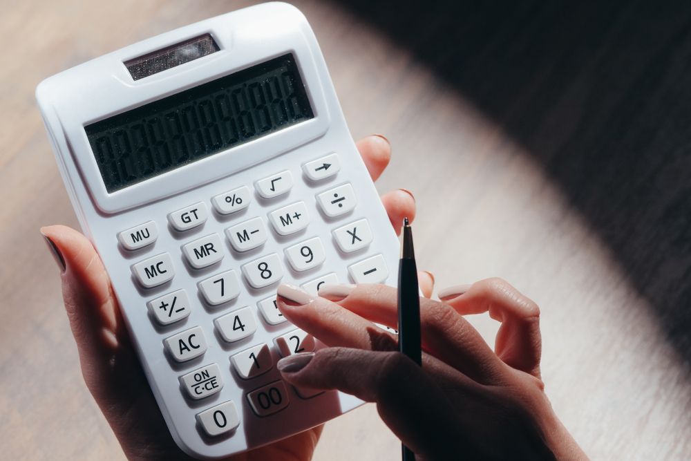 Person using a calculator with papers on a desk