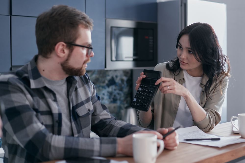 Couple going through household finances at a table, working through loan affordability on paper