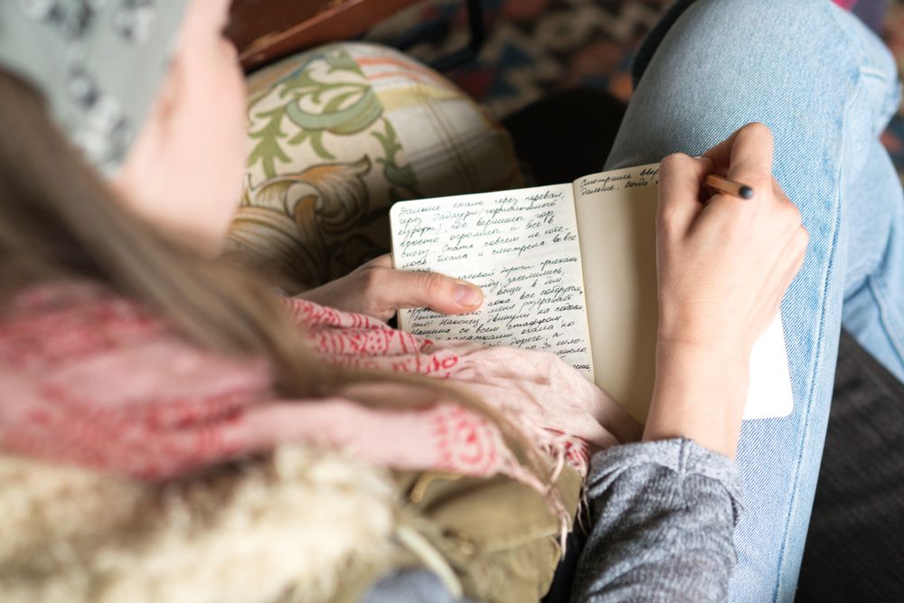 Person writing in a notebook with a pen