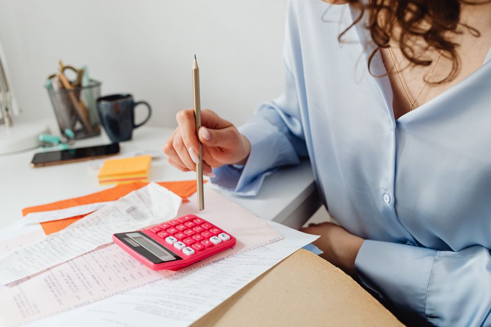 Person using a calculator with papers on a desk