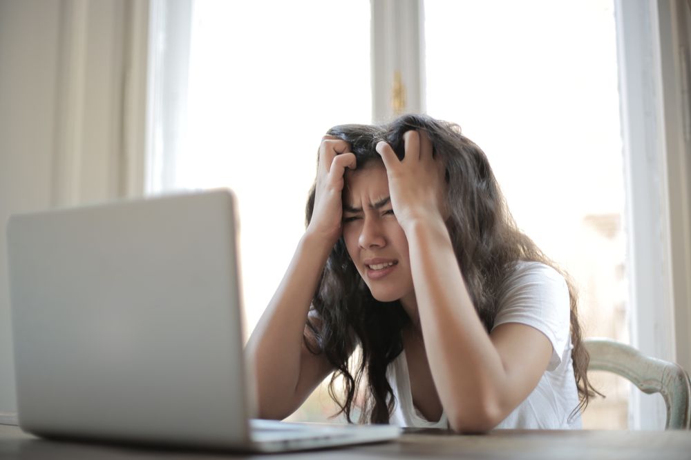 Stressed person with their head in their hands, worrying about a loan while blacklisted