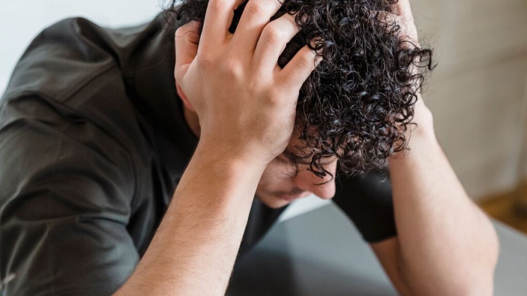 Person with head in hands thinking about repaying a loan