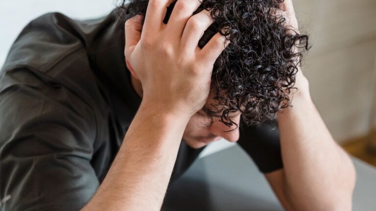 Person with head in hands thinking about repaying a loan