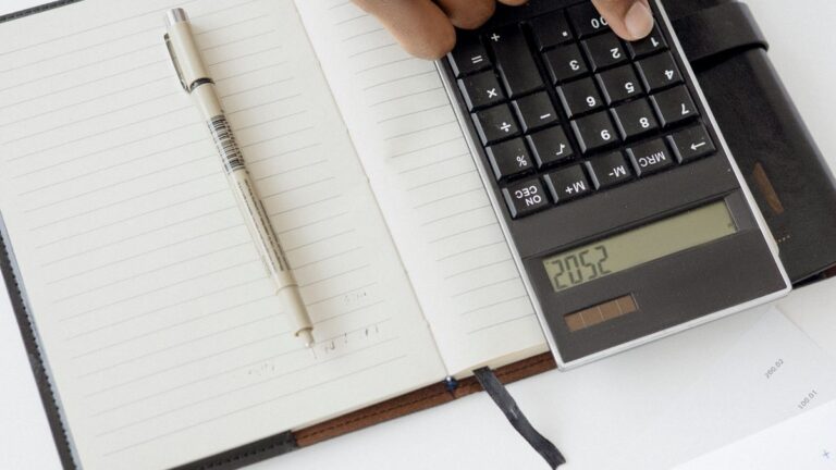 Person using a calculator with papers on a desk