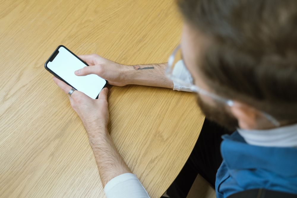 Person using a smartphone at a table, checking a salary advance app before using it