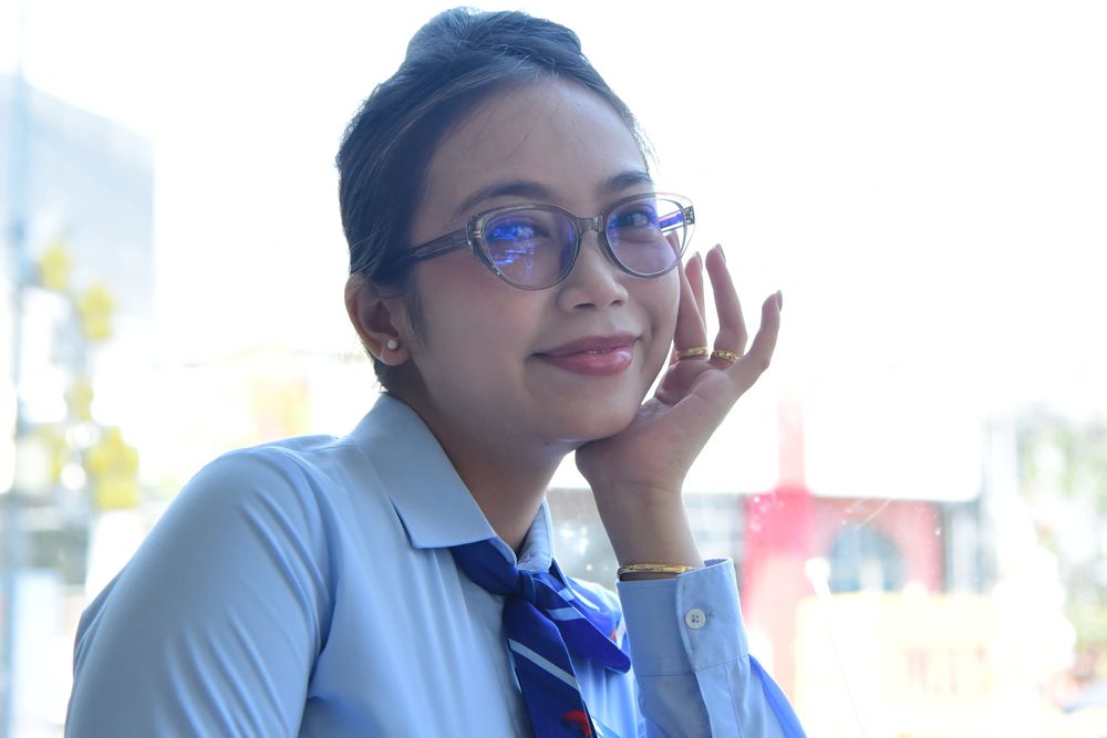 Woman with glasses smiling at a desk, a side hustle selling goods from home